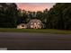 Stately brick home with lush lawn, mature trees, and warm exterior lighting at dusk at 307 Bellingrath Ct, Peachtree City, GA 30269