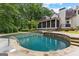 Backyard features an in-ground pool with stone accents, screened porch, and verdant landscaping at 307 Bellingrath Ct, Peachtree City, GA 30269