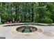 A luxurious in-ground pool and hot tub are surrounded by a concrete patio and a backdrop of mature trees at 307 Bellingrath Ct, Peachtree City, GA 30269