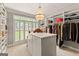 Spacious walk-in closet with custom shelving, storage island, and a stylish chandelier at 307 Bellingrath Ct, Peachtree City, GA 30269