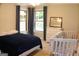 Bright bedroom with a queen-sized bed, a crib, and two windows with patterned curtains at 1310 Larkview Sw Dr, Lilburn, GA 30047