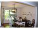 Stylish dining room featuring a long wooden table, white chairs, a modern light fixture, and views from a window at 1310 Larkview Sw Dr, Lilburn, GA 30047