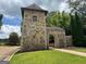 Charming community entrance with stone gatehouse, arched entrance, and manicured lawn at 4309 Giverny Blvd, Fairburn, GA 30213