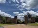 Grand entrance to Le Jardin with stone pillars, an iron gate, and lush landscaping at 4309 Giverny Blvd, Fairburn, GA 30213