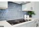 Modern kitchen featuring stylish blue tile backsplash, white cabinets, and a sleek cooktop at 4484 Eastbrook Pl # 54B, Snellville, GA 30039
