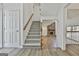 Open foyer with hardwood floors, staircase, and a glimpse into the living room with a cozy fireplace at 205 Shadowood Ln, Peachtree City, GA 30269