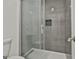 Modern shower features gray tile, glass doors, built in shelf and grab bar at 205 Shadowood Ln, Peachtree City, GA 30269