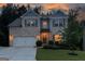 Elegant two-story home with warm exterior lighting, a well-kept lawn, and an inviting facade at twilight at 302 Aspen Valley Ln, Dallas, GA 30157