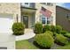 Close-up of a home's entrance with manicured bushes, an American flag, and a stone-accented walkway at 302 Aspen Valley Ln, Dallas, GA 30157