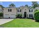 Elegant home featuring a manicured lawn, a large arched front door, and a three car garage at 5245 Cottage Farm Rd, Johns Creek, GA 30022
