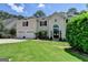 Elegant home featuring a manicured lawn, a large arched front door, and a three car garage at 5245 Cottage Farm Rd, Johns Creek, GA 30022