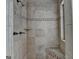 Shower featuring travertine walls, mosaic accents, a built-in bench, and a window at 5245 Cottage Farm Rd, Johns Creek, GA 30022