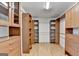 Spacious walk-in closet with custom shelving, hanging rods, and wood flooring at 5245 Cottage Farm Rd, Johns Creek, GA 30022