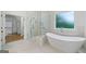 Bright bathroom with elegant soaking tub, glass shower, and marble tile at 103 Maddox Rd, Buford, GA 30518