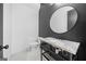 Modern bathroom featuring a marble countertop, round mirror, and sleek black and white design at 103 Maddox Rd, Buford, GA 30518