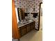 Functional bathroom featuring a single sink vanity, floral wallpaper, and a mirror with ample counter space at 90 Cabriolet Trail, Mcdonough, GA 30253