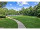 Sidewalk leads to a park area of well-manicured green grass and shady trees at 3725 Downing Dr, Cumming, GA 30040