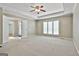Large carpeted bedroom with tray ceilings, fan, and large windows offers ample space and natural light at 118 Whitfield Run, Peachtree City, GA 30269