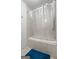 Bathroom featuring a shower-tub combo, neutral tile, and blue rug at 1290 Shadowlawn Ne Dr, Conyers, GA 30012
