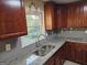 Well-lit kitchen featuring granite counters, stainless steel sink, and wood cabinets at 655 Shellnut Dr, Forest Park, GA 30297