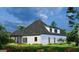 Exterior view of a lovely white brick home featuring a covered porch and a lush, green backyard with flowers at 1077 Crooked Creek Rd, Lithonia, GA 30058