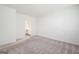Empty bedroom with light-colored carpet and white walls with an open doorway to a bathroom at 7301 Cranleigh St, Covington, GA 30014