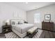 A staged bedroom with gray flooring has a Queen bed and neutral decor, and light walls at 7301 Cranleigh St, Covington, GA 30014
