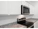 Close-up of stainless steel oven and microwave in kitchen with granite countertops and white backsplash at 7301 Cranleigh St, Covington, GA 30014