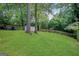 Expansive backyard featuring lush green grass, mature trees, storage building, and a charming fence at 792 Mimosa Se Dr, Marietta, GA 30060