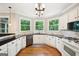 Bright kitchen with white cabinetry, black countertops, hardwood floors, and windows offering views of the outdoors at 1285 Willow Park Way, Cumming, GA 30041
