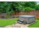 Backyard spa featuring a hot tub with stone pavers, landscaping, and a wooden privacy fence at 10980 Pinehigh Dr, Alpharetta, GA 30022