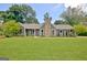 Charming single-story home with a stone chimney, complemented by a lush green lawn and mature trees at 110 Chesterfield Ct, Fayetteville, GA 30214