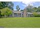 Charming single-story home with a stone chimney, complemented by a lush green lawn and mature trees at 110 Chesterfield Ct, Fayetteville, GA 30214