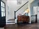 Elegant foyer with hardwood floors, staircase, decorative chest, and stylish lighting at 7093 Vaughn Rd, Canton, GA 30115