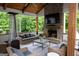 Covered outdoor living area featuring a brick fireplace, comfortable seating, and a view of the lush greenery at 7093 Vaughn Rd, Canton, GA 30115