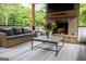 Covered outdoor living area featuring a brick fireplace, comfortable seating, and a view of the lush greenery at 7093 Vaughn Rd, Canton, GA 30115