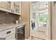 Butler's pantry with wine fridge, glass cabinets, marble countertops and views to the breakfast room at 121 Fairway Overlook, Woodstock, GA 30188