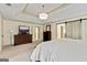 This primary bedroom features a tray ceiling, a modern light fixture, and a large dresser with TV at 121 Fairway Overlook, Woodstock, GA 30188