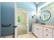 Bathroom with blue walls, a white vanity, round mirror and a view to an adjacent bedroom at 115 Edgewater Way, Peachtree City, GA 30269