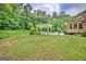 An expansive backyard with manicured lawn features a pool, lounge seating, and lush landscaping at 310 Westbourne Dr, Tyrone, GA 30290