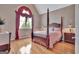 Spacious bedroom with four-poster bed, hardwood floors, and a large window with decorative curtains at 310 Westbourne Dr, Tyrone, GA 30290