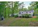 Landscaped backyard with outdoor fireplace, back deck, trees, and green grass at 7025 Stone Wood Nw Dr, Kennesaw, GA 30152