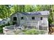 View of home with a large wooden deck and outdoor seating surrounded by lush green trees at 7025 Stone Wood Nw Dr, Kennesaw, GA 30152