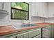 A close view of the kitchen with wooden countertop, stainless steel sink, and subway tile backsplash at 7025 Stone Wood Nw Dr, Kennesaw, GA 30152