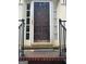 Close-up of a weathered front door with sidelights, black iron railing, and brick steps at 974 Bloomfield Dr, Lawrenceville, GA 30044