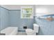 Retro blue bathroom with tiled walls, a bathtub, and a window providing natural light for a refreshing start to the day at 1189 E Fayetteville Rd, Riverdale, GA 30296