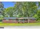 Charming one-story brick home featuring mature trees and traditional curb appeal with green shutters on the windows at 1189 E Fayetteville Rd, Riverdale, GA 30296