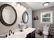 Bathroom with a double vanity, black hardware, oval mirrors, and neutral wall and floor tiles at 3359 Villa Ln, Douglasville, GA 30135