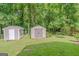Two storage sheds with neutral paint surrounded by green lawn and trees in backyard at 3781 Deercreek Dr, Powder Springs, GA 30127