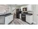 Kitchen area with white cabinets, black appliances and laminate flooring at 142 Holly Mill Village Dr, Canton, GA 30114